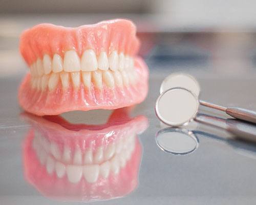 Dentures and dental mirror on a reflective table