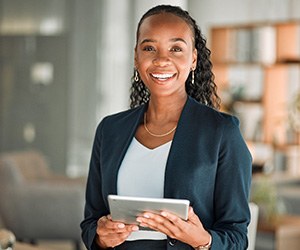 Woman smiling while holding tablet in office