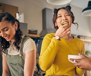 Woman smiling while eating lunch with friends in kitchen