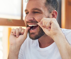 Man flossing his teeth in bathroom