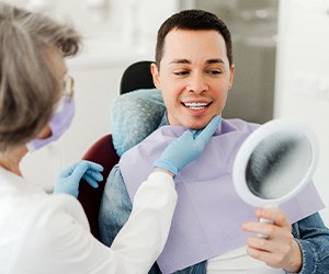 Man smiling at reflection in mirror with dentist