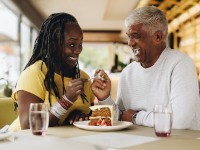 Couple smiling while eating dessert together at restaurant