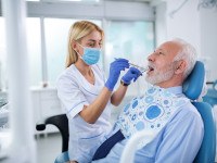 Dentist checking patient's teeth and dental implants in treatment chair