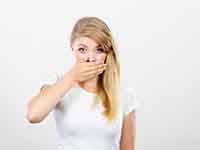 Woman with hand over her mouth, hiding stained teeth