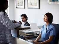 Dental team member talking to patient at front desk