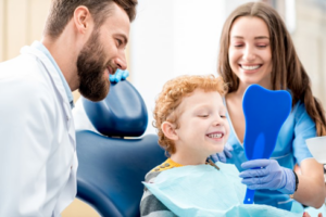 Pediatric dentist and dental assistant using a mirror to let a child see his new fillings