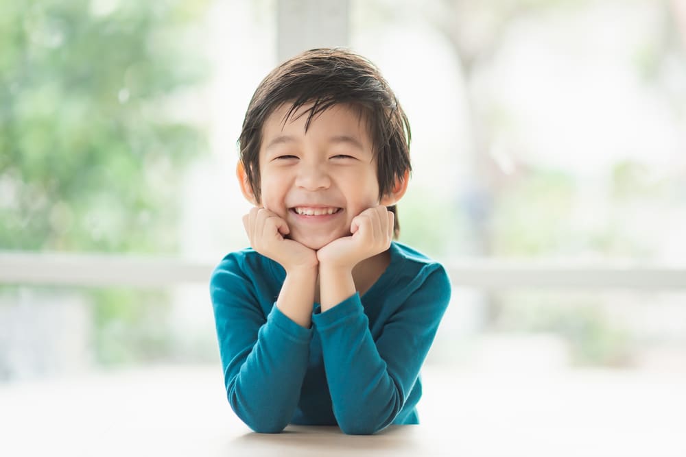 Smiling young boy resting his chin on his hands